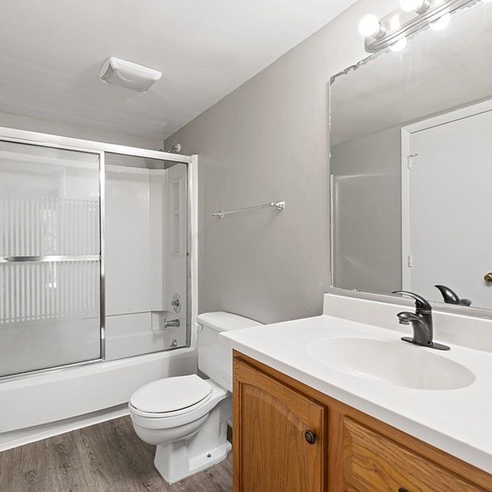 Elegant bathroom with modern fixtures, featuring a sleek glass shower, spacious vanity, and warm wood cabinetry.