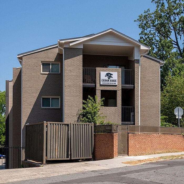 Charming Cedar Oaks Condominiums with modern architecture, surrounded by lush greenery and inviting balconies.