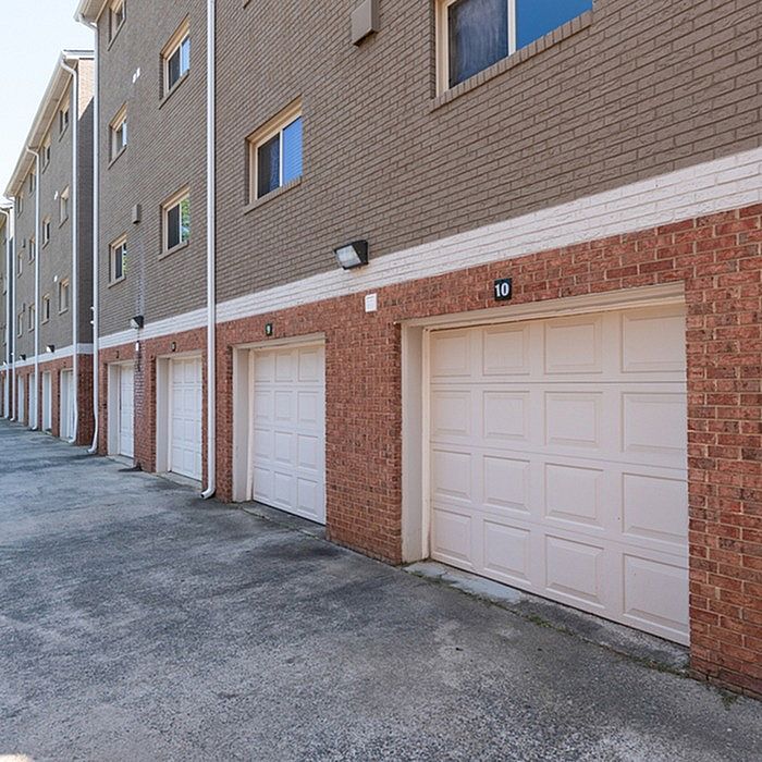 Modern townhouse exterior featuring multiple garages and brick facade, offering ample parking and stylish urban living.