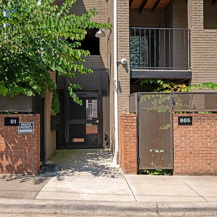 Charming apartment entrance with a gated entryway, modern brick design, and lush greenery.