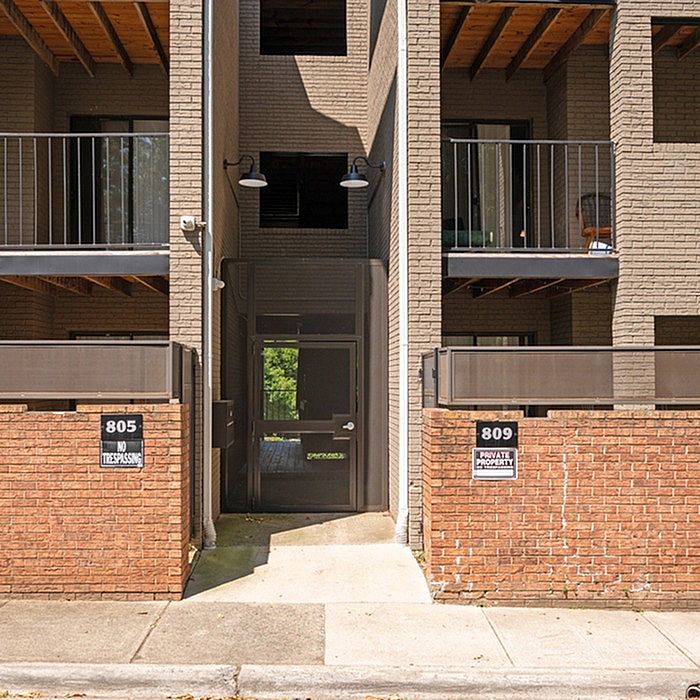 Modern apartment entrance with sleek balconies and stylish brick facade.