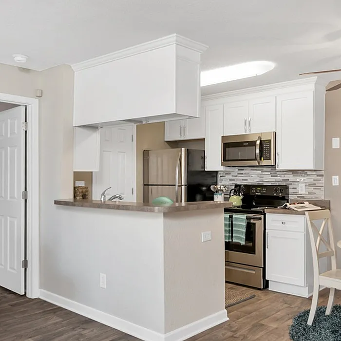 Elegant kitchen with modern appliances, sleek white cabinets, and a cozy breakfast bar.