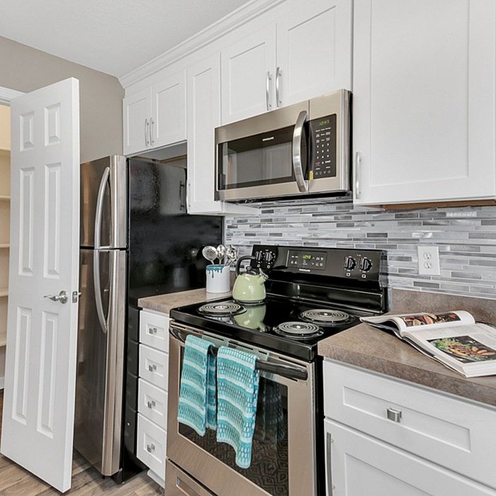 Modern kitchen with sleek stainless steel appliances, elegant white cabinetry, and a stylish tiled backsplash.