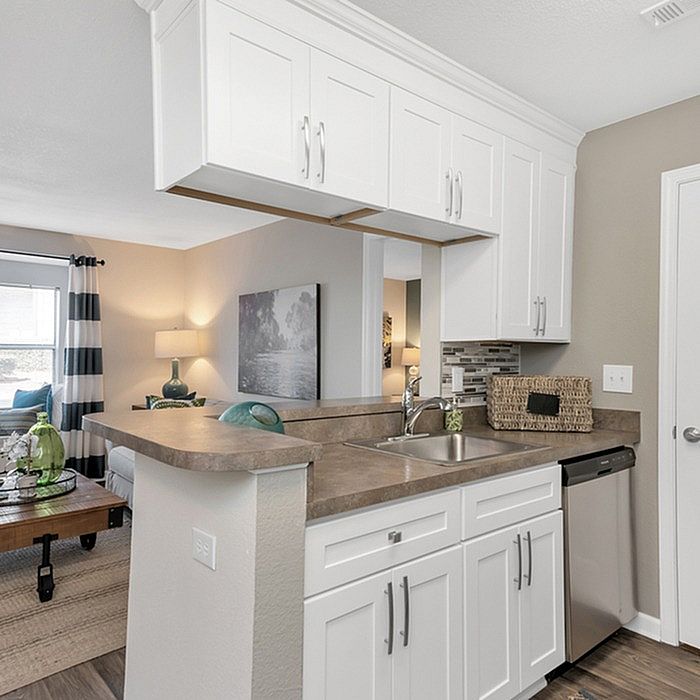 Chic open kitchen design with sleek white cabinets and modern appliances, seamlessly connecting to a cozy living space.