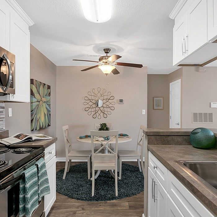 Contemporary kitchen with sleek countertops, stainless steel appliances, and an inviting dining area under a stylish ceiling fan.