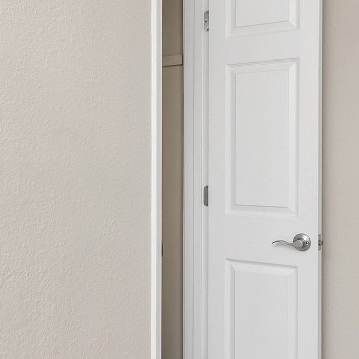 Sleek white interior door with modern handle, opening to reveal a cozy closet space, perfect for organized living.