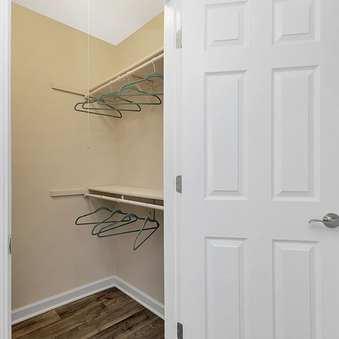 Bright and inviting walk-in closet with spacious shelving and light wooden flooring, perfect for organization and storage.