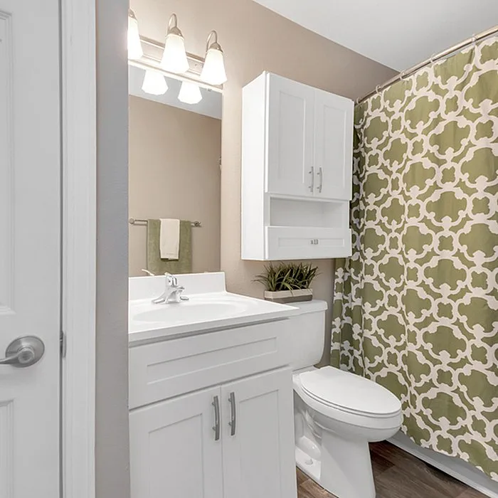 Elegant bathroom with modern fixtures, sleek white cabinetry, and stylish green patterned curtain, creating a fresh and inviting space.