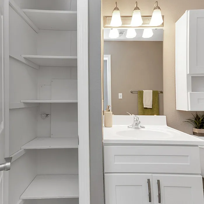 Elegant bathroom space featuring a pristine white vanity with ample shelving, chic lighting fixtures, and modern decor.