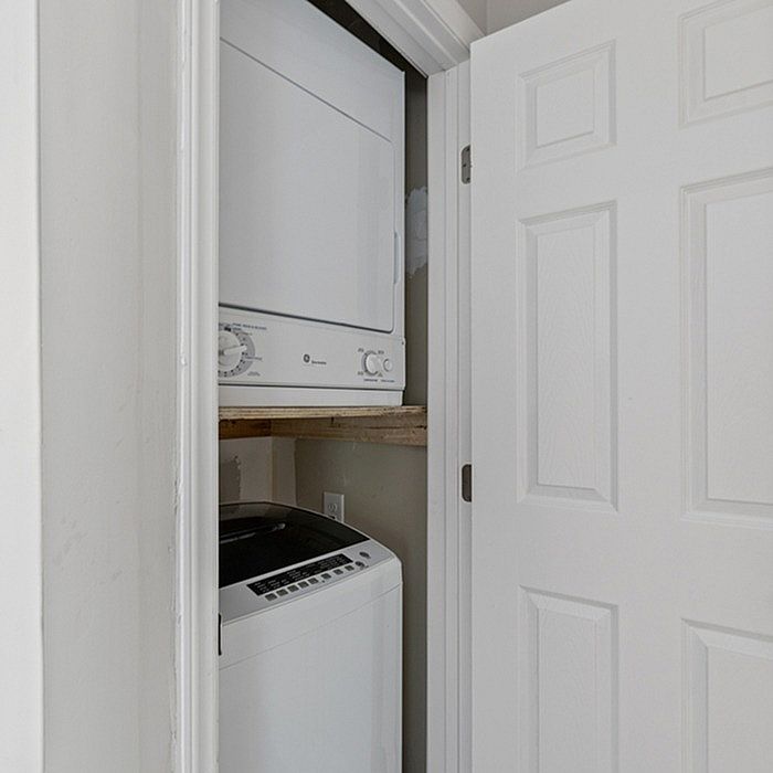 Compact, built-in laundry unit featuring a stacked washer and dryer, perfect for maximizing apartment space effectively.