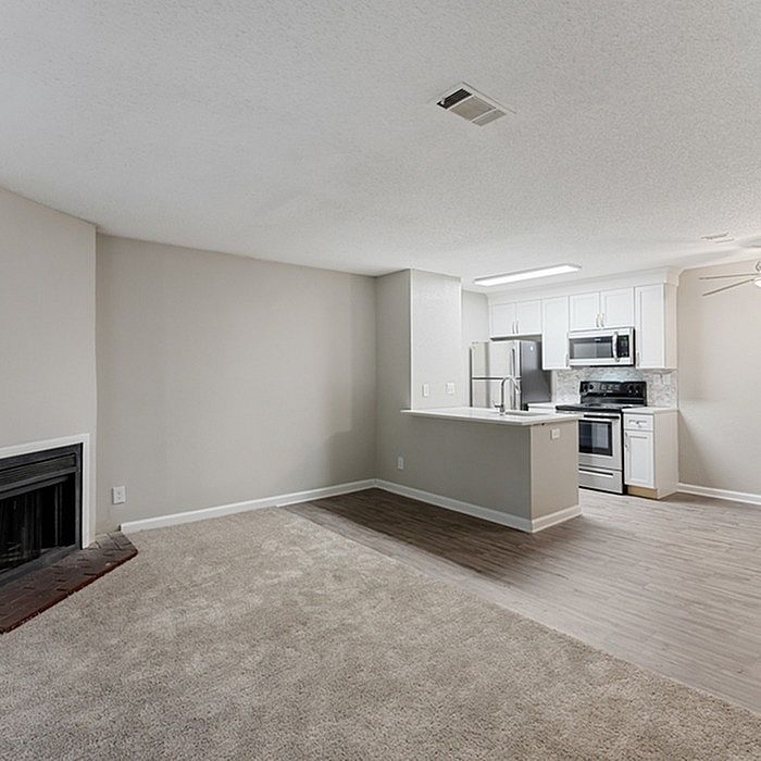 Modern open-concept living space with cozy fireplace, stylish kitchen with stainless steel appliances, and elegant flooring.