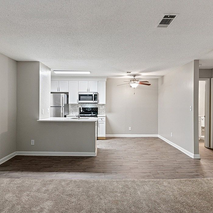 Contemporary open-plan living room with sleek kitchen, stainless steel appliances, and elegant wood floors.