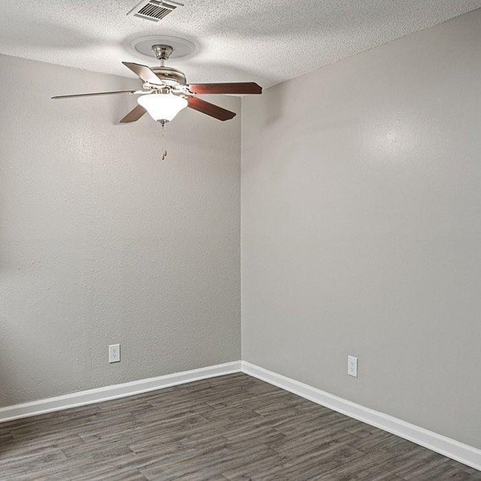 Bright and modern room with sleek wood flooring, neutral gray walls, and a stylish ceiling fan, perfect for a cozy living space.