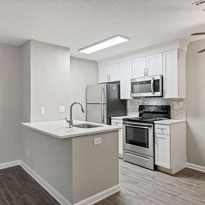 Modern apartment kitchen with elegant white cabinetry, sleek stainless steel appliances, and a stylish breakfast bar.