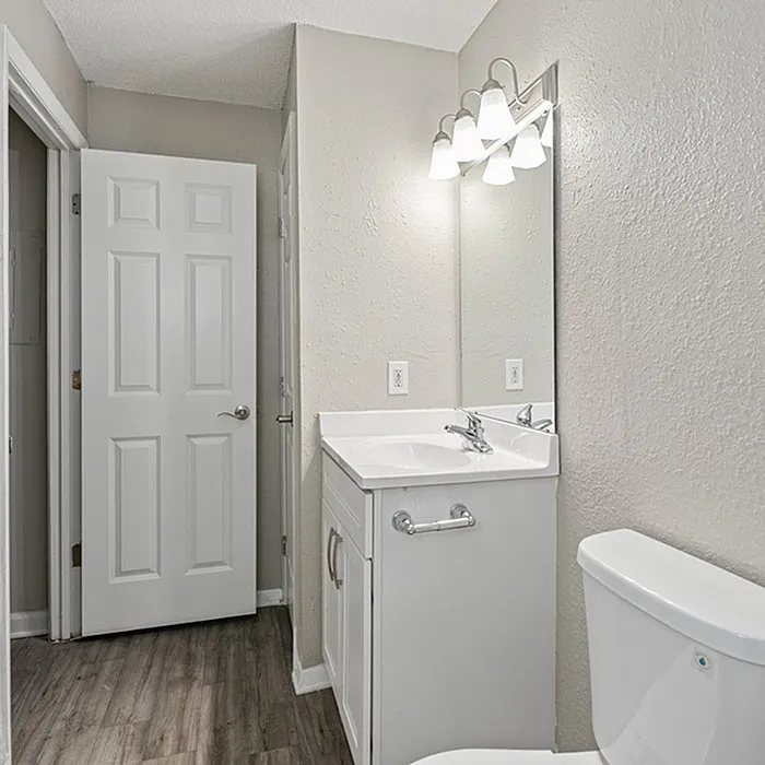 Modern bathroom in neutral tones featuring a sleek vanity with a large mirror and elegant lighting.