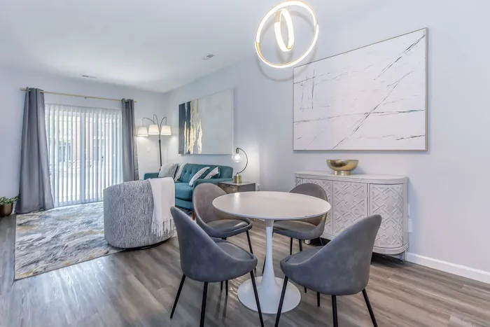 Bright and modern living area with elegant decor, featuring a cozy sofa, sleek dining table, and artistic wall art, bathed in natural light.