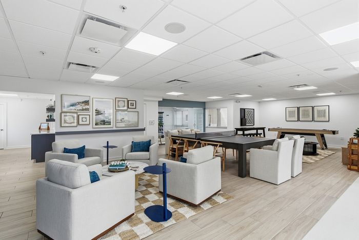Modern communal lounge with plush seating, elegant decor, and games tables in a bright, open space.