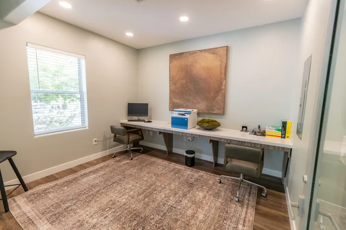 Bright and inviting home office with a modern desk, sleek chair, and elegant decor, featuring natural light from a large window and warm wood flooring.