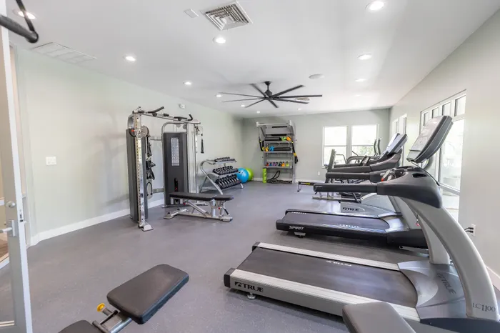 Bright modern fitness room equipped with state-of-the-art treadmills, weight machines, and free weights, offering a perfect workout environment.