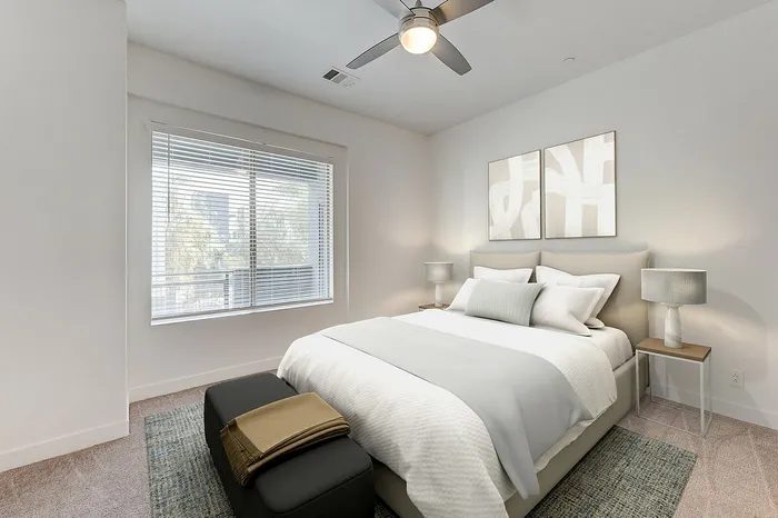 Bright and airy bedroom with modern decor, featuring a comfortable bed, stylish lamps, and a cozy carpeted floor, perfect for relaxation.
