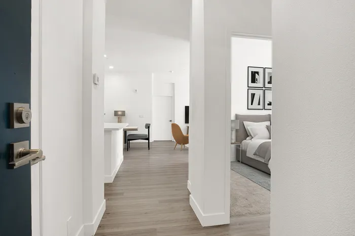 Inviting apartment entrance leading to a stylish open-concept living area with modern decor and a cozy bedroom.