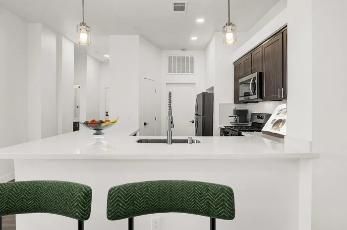 Modern kitchen with sleek countertop, elegant pendant lighting, and stainless steel appliances, perfect for stylish culinary adventures.