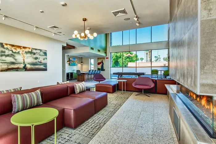 Modern apartment lounge with chic seating, vibrant art, and large windows offering natural light ambiance.