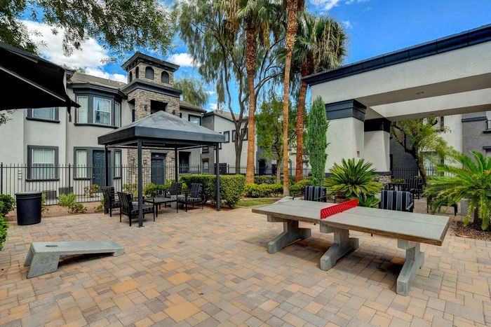 Charming outdoor courtyard with elegant seating, lush greenery, and a modern ping pong table for leisure in a stylish apartment complex.