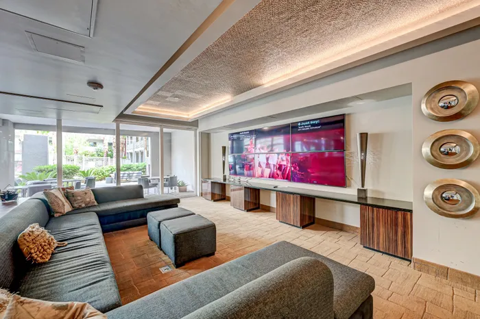 Luxurious clubhouse with a sleek, contemporary design featuring a plush sectional sofa, expansive windows, and a state-of-the-art entertainment center.