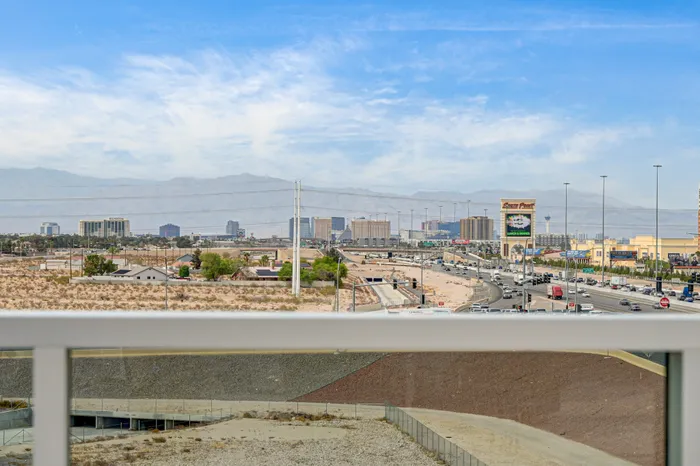 Stunning panoramic view from the apartment balcony showcasing a vibrant cityscape under a clear blue sky, highlighting proximity to urban amenities.