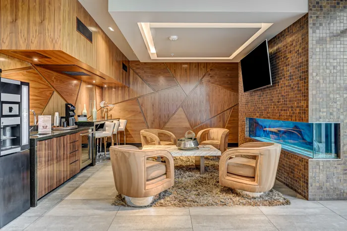 Contemporary lounge area with cozy seating, sleek wood paneling, stylish bar, and vibrant aquarium accent.
