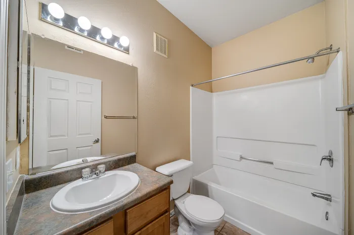 Modern bathroom featuring a sleek sink, bright vanity lights, and a pristine bathtub with neutral d&eacute;cor.