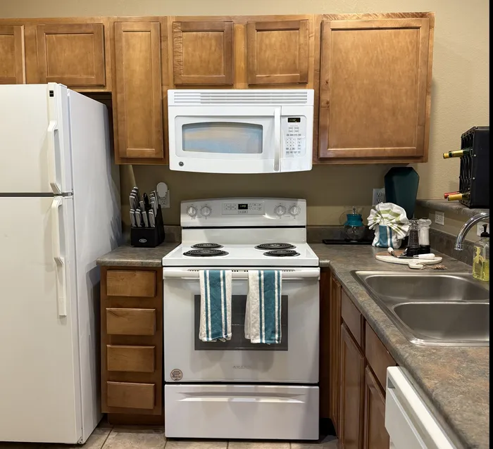 Charming kitchen with warm wooden cabinetry, modern appliances, and elegant tile flooring.