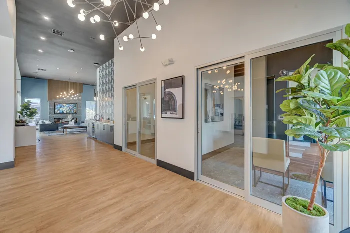 Modern open-concept living space with stylish lighting, large windows, and inviting seating area, accentuated by a chic plant and elegant decor.