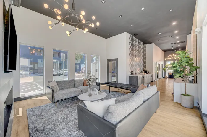 Luxurious modern living room with chic gray sofas, elegant lighting fixtures, and large windows providing ample natural light.