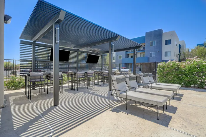 Modern outdoor lounge area with stylish pergola, cozy seating, and sleek bar tables, perfect for relaxation and social gatherings.