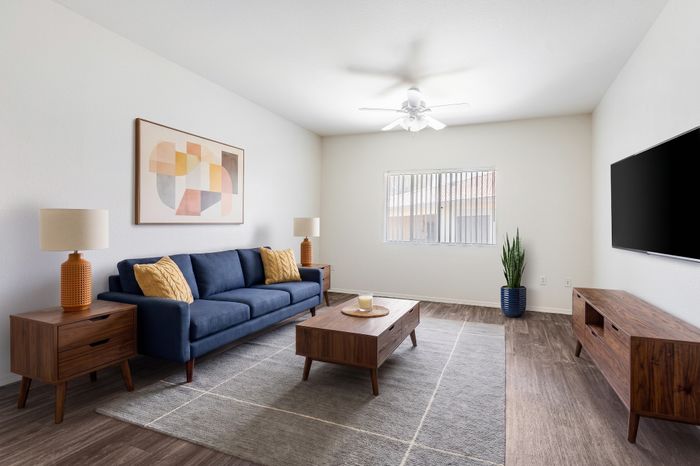 Modern living room with a stylish blue sofa, mid-century wooden furniture, and contemporary artwork, exuding warmth and elegance.