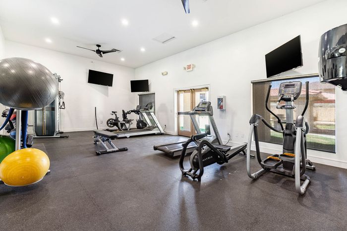 Modern fitness center featuring state-of-the-art exercise equipment, treadmills, and free weights in a well-lit, spacious room.