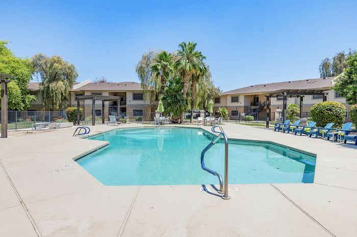 Inviting outdoor pool surrounded by lush greenery and comfortable seating in a modern apartment complex.