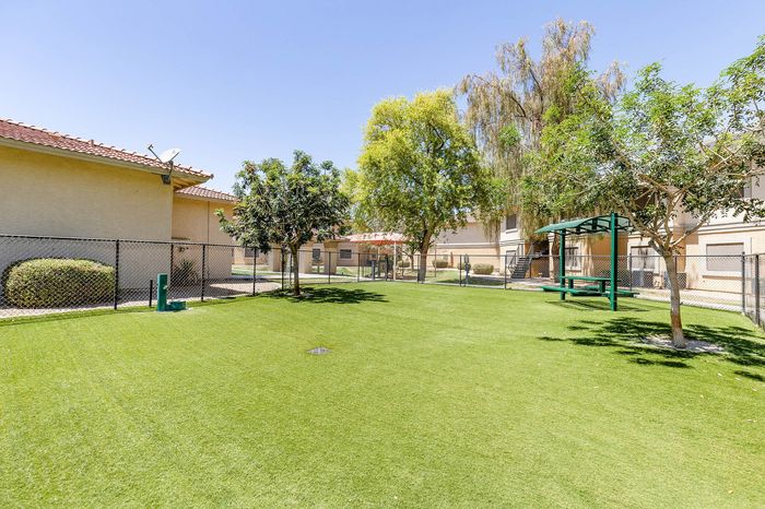 Expansive green outdoor space with lush lawns and mature trees at a charming residential complex, perfect for relaxation and recreation.