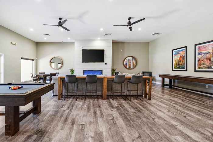 Spacious and modern game room featuring a pool table, elegant bar seating, and vibrant artwork on the walls.