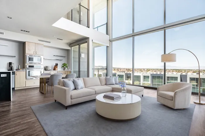 Luxurious open-concept living room with floor-to-ceiling windows, modern kitchen, and stunning city views.