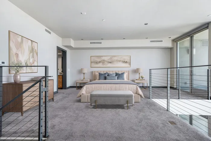 Luxurious master bedroom with elegant decor, plush carpet, and abundant natural light from large windows.