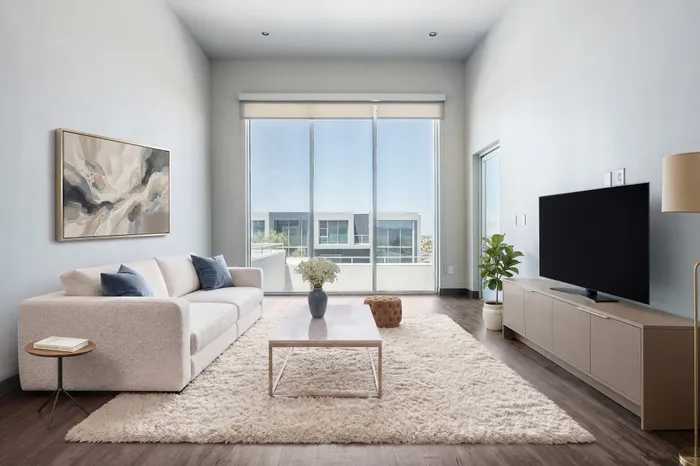 Elegant living room with a plush sofa, modern decor, floor-to-ceiling windows offering a stunning city view, and abundant natural light.