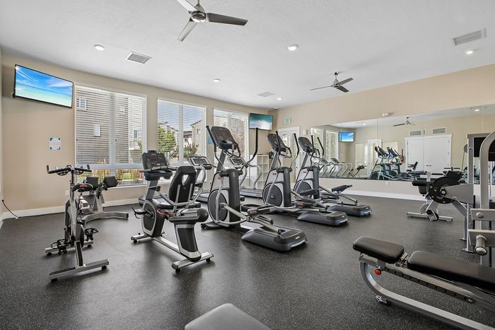 Modern fitness center with state-of-the-art cardio machines, weights, and expansive mirrors for a comprehensive workout experience.
