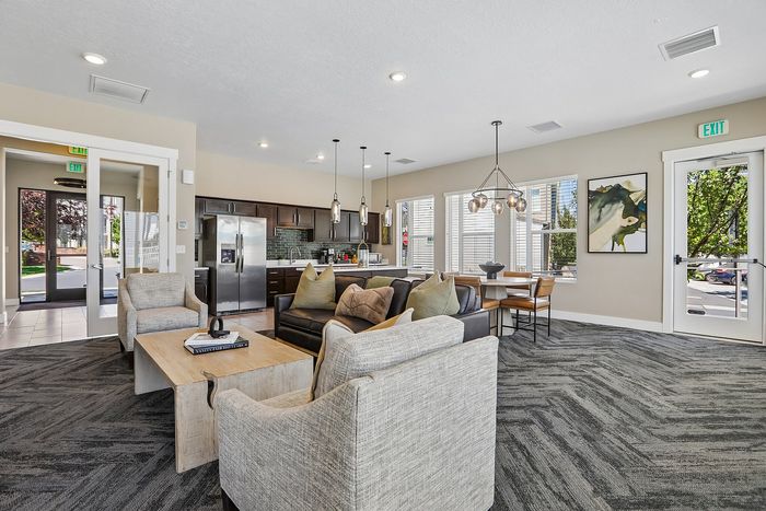 Modern open-concept living area featuring a stylish kitchen with stainless steel appliances, cozy lounge seating, and elegant pendant lighting.