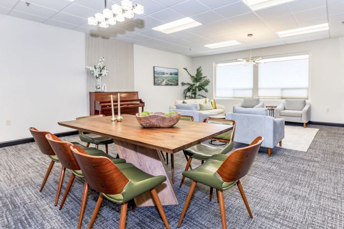 Modern clubhouse with stylish wood dining table and plush seating, showcasing elegant decor and ample natural light.