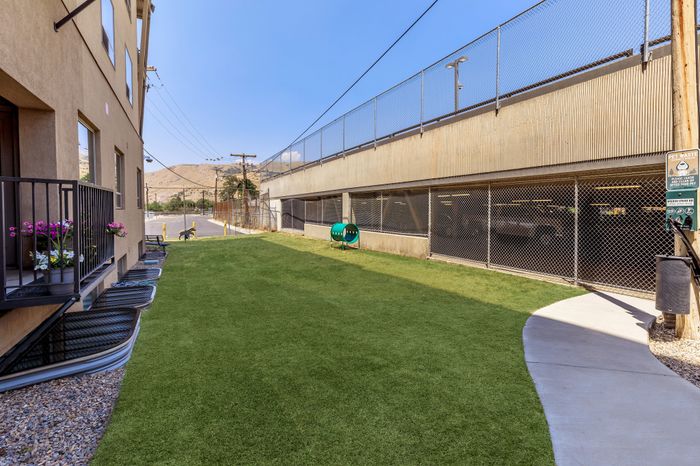Charming apartment exterior featuring a lush green lawn and vibrant potted flowers, perfect for outdoor relaxation.