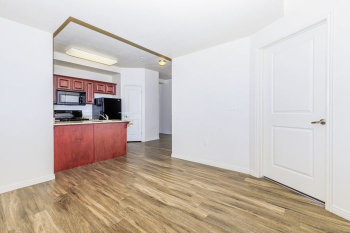Bright modern kitchen with rich wooden cabinetry, sleek appliances, and elegant wood flooring, offering a welcoming open space.