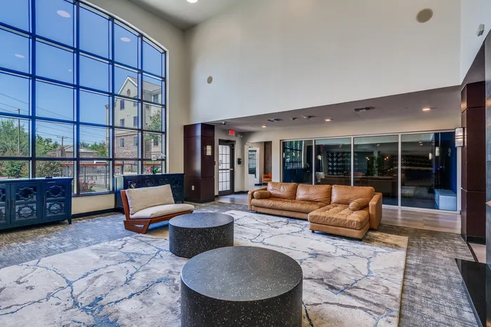 Inviting lounge area featuring large windows, plush leather seating, and modern décor, offering a sophisticated ambiance.